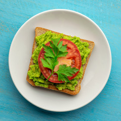 Avocado toast made from bran bread sprinkled with black sesame and chili peppers and a slice of tomato
