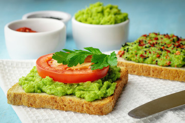 Avocado toasts with a slice of tomato, as well as black sesame and chili peppers and spices in the background