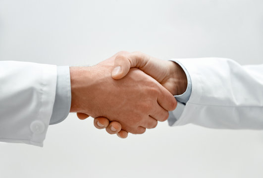 healthcare, profession, people and medicine concept - close up of two male doctors shaking hands