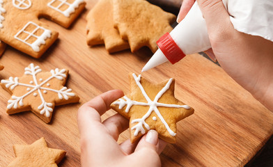Christmas bakery. Woman decorating homemade gingerbread cookie