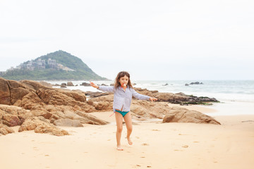 Fototapeta na wymiar Five-year-old girl playing on the sandy beach of the sea