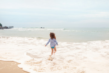 Fototapeta na wymiar Five-year-old girl playing on the sandy beach of the sea