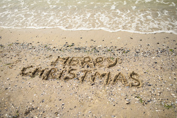 Merry Christmas written on tropical beach sand, copy space. Holiday concept, top view