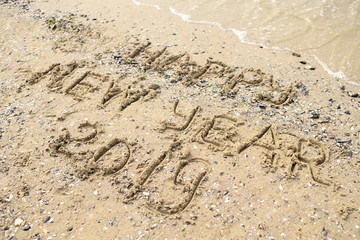 Happy new year written on tropical beach sand, copy space. Holiday concept