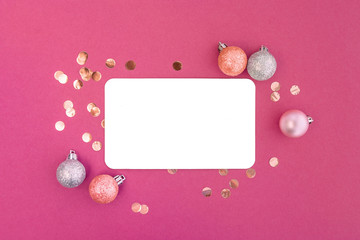 Fototapeta na wymiar Frame of christmas balls and confetti with blank card mockup on dark coral pink background.