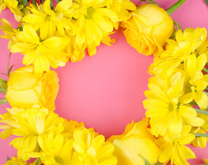 Bright yellow chrysanthemum flowers and roses forming a circle frame on a bright pink paper background, copy space in the center for your text (flat lay, top view)