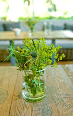 Holztisch dekoriert mit grünen Blumen
