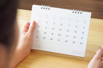 calendar page with female hand holding pen on desk table