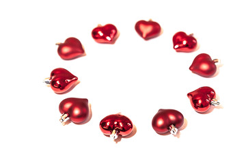 circle of red Christmas decorations in shape of heart on white background