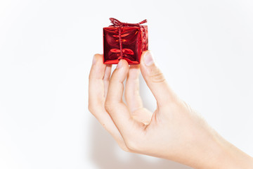 small red box in fingers om hand on white isolated background, small Christmas gift