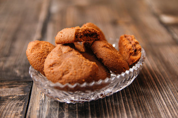Cookies filled with chocolate cream in crystal bowl on old wooden table