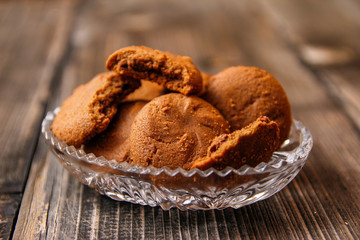 Cookies filled with chocolate cream in crystal bowl on old wooden table