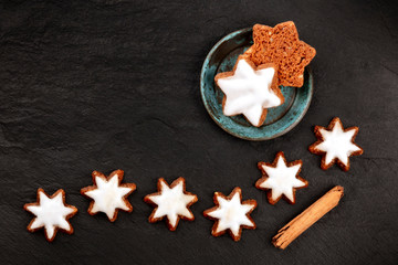 Obraz na płótnie Canvas A photo of Zimsterne, traditional German cinnamon star cookies, shot from the top on a black background with copy space