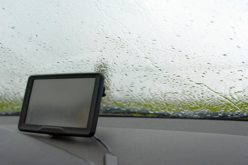 Inside of a car with rain on windshield window and GPS navigation system in bad weather
