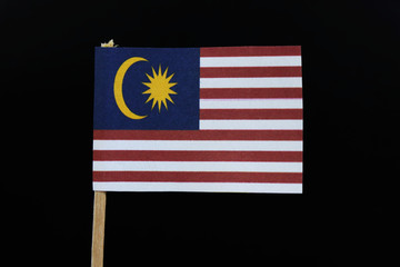 A unique flag of Malaysia on toothpick on black background. Consists of Fourteen horizontal stripes alternating red and white; in the canton, a yellow crescent and 14-point star on a blue field.