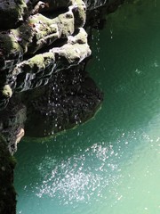 water drops fall from a stone cliff into a river