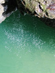 water drops fall from a stone cliff into a river