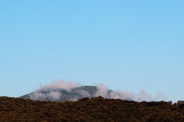 against the blue sky is visible a mountain shrouded in clouds