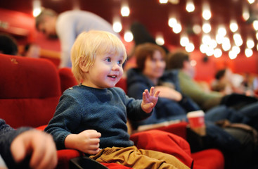 Cute toddler boy watching cartoon movie in the cinema