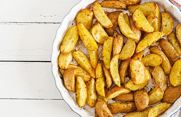 Ruddy Baked potato wedges with garlic on a white background. Flat lay. Top view.