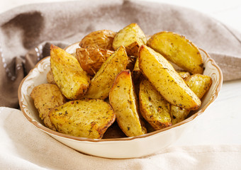 Ruddy Baked potato wedges with garlic on a white background.
