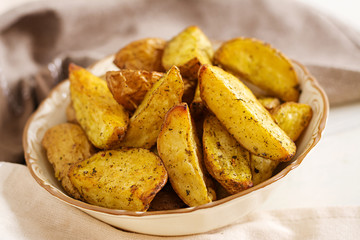 Ruddy Baked potato wedges with garlic on a white background.