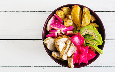 Buddha bowl dish with chicken fillet, beked potato, avocado, cabbage, watermelon radish and chia seeds. Detox and healthy food bowl concept. Top view