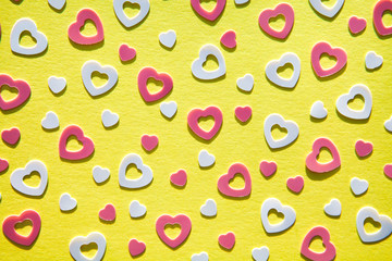 Pastel colored heart confetti scattered on yellow background.  Modern trendy  flat lay design background for invitations, greeting cards, banners, albums. Valentines day, wedding, baby shower concept
