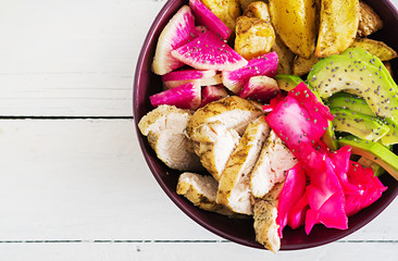 Buddha bowl dish with chicken fillet, beked potato, avocado, cabbage, watermelon radish and chia seeds. Detox and healthy food bowl concept. Top view
