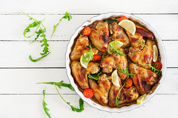 Baked chicken wings in plate on wooden table. Top view.