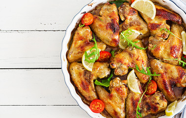 Baked chicken wings in plate on wooden table. Top view.