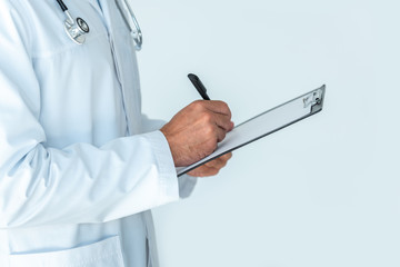 cropped image of doctor with stethoscope on shoulders writing something in clipboard isolated on white