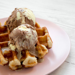 Traditional belgian waffle with icecream on pink plate over white wooden surface, side view. Close-up.