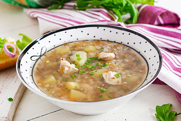 Buckwheat soup with chicken  in a plate, bread with mustard ang red onion on a wooden white table.