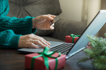 Christmas sales. Woman shopping with credit card by laptop in home interior. Xmas. Planing holidays.