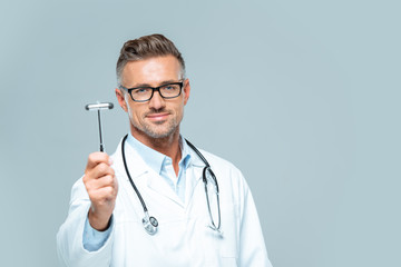 handsome neurologist with stethoscope on shoulders showing reflex hammer isolated on white - obrazy, fototapety, plakaty