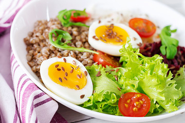 Buckwheat porridge buddha bowls with beetroot, cabbage, boiled eggs and  fresh tomato on white table. Healthy breakfast.