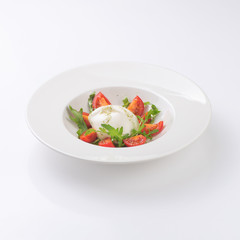 Salad with mozzarella on a white plate. Isolated.