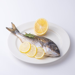 Dorada fish with lemon on a white plate. Isolated.
