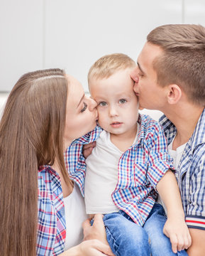 Little boy having the attention of his parents kissing him