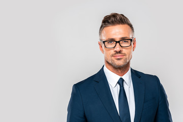 portrait of handsome businessman in suit and glasses looking at camera isolated on white