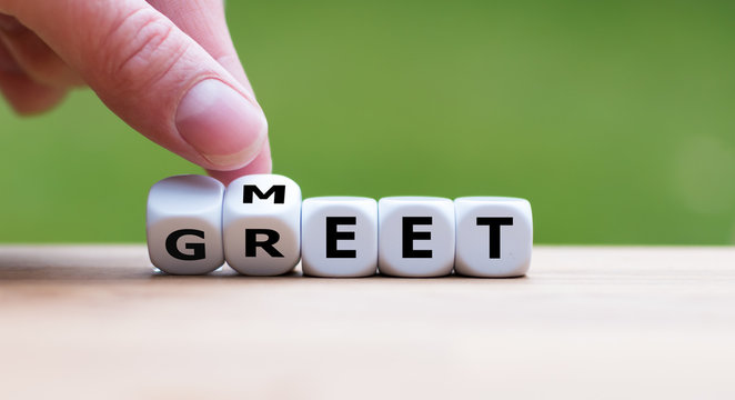 Hand is turning a dice and changes the word "Meet" to "Greet"