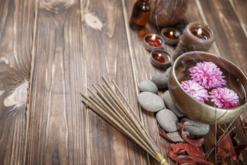 Singing bowl with candles with pebbles on dark wooden background
