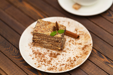 Piece of cake Napoleon on white plate. Russian cuisine, layered cake with chocolate cream, close up view
