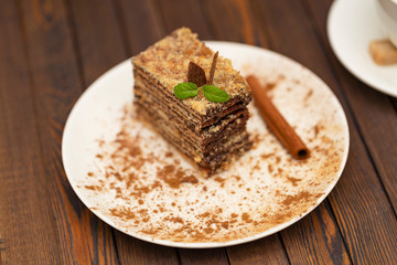 Piece of cake Napoleon on white plate. Russian cuisine, layered cake with chocolate cream, close up view