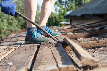 Worker demolishing old wooden boards from the roof  with crowbar tool