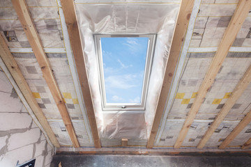 Mansard with environmentally friendly and energy efficient skylight window against blue sky. Room...