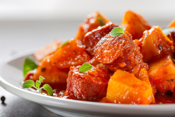 Stew made from pork fried sausages with potatoes and tomato sauce