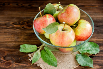 Fresh garden apples with leaves on dark wooden background. Autumn harvest