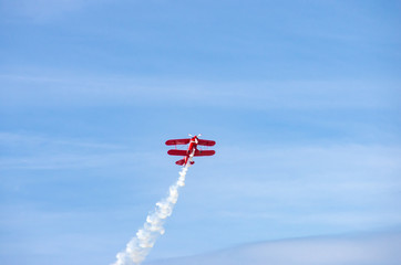 red airplane doing acrobatics in blue sky © GaiBru Photo
